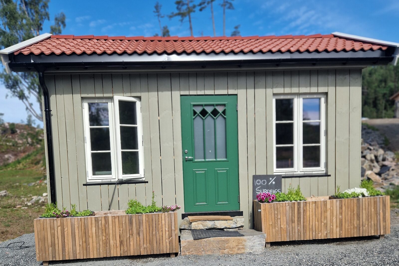 Den grønne bua hos Enklere Bondeliv, med grønn dør og blomsterkasser