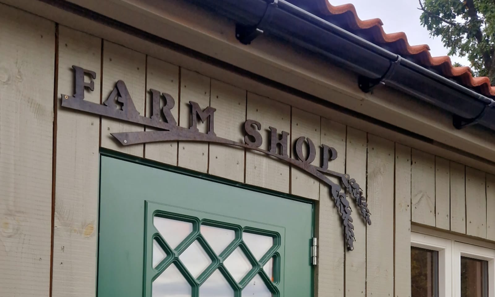 Smijernsskilt med teksten FARM SHOP over den grønne døren til bua